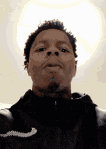 a man in a black jacket is taking a selfie with the sun behind him .