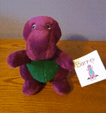 a purple barney stuffed animal with a tag attached to it