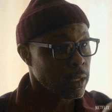 a man wearing glasses and a beanie with netflix written on the bottom right