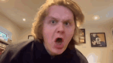 a man with long blonde hair is making a funny face with his mouth open