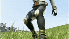 a man in a superhero costume is walking through a field of grass .