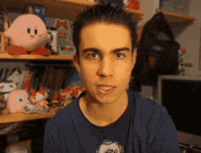 a young man is standing in front of a shelf filled with stuffed animals