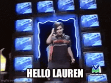a woman is standing in front of a bunch of televisions and says hello lauren .