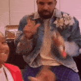 a man with a beard wearing a denim jacket with flowers on it