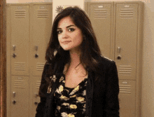 a woman in a floral dress is standing in front of a row of lockers
