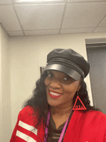 a woman wearing a black hat and earrings with the letter eaa on them