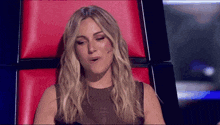 a woman with blonde hair is sitting in a red chair with her eyes closed