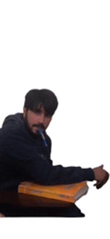 a man is sitting at a table with a book and a pen in his hand .