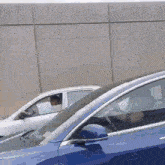 a blue car is parked next to a white car with a sign on the window