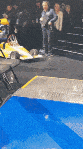 a man wearing headphones is standing in front of a yellow race car