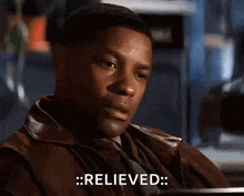 a man in a brown leather jacket is sitting at a table and says relieved