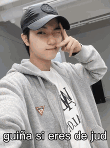 a man wearing a guess hoodie and a hat makes a face