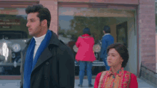 a man and a woman are standing in front of a car showroom