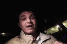 a man with braces on his teeth is smiling and waving his hand in the dark .