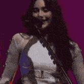 a woman is singing into a microphone while holding a guitar on a stage .