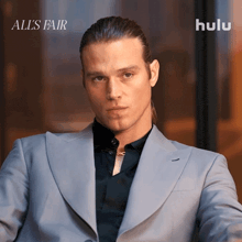 a man in a suit is sitting in front of a sign that says hulu on it