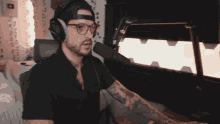 a man wearing headphones and glasses says f * cker in front of a microphone