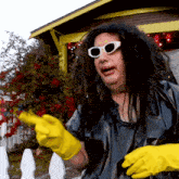 a person wearing sunglasses and yellow gloves is pointing