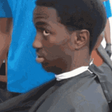 a man is getting his hair cut at a barber shop and making a funny face .
