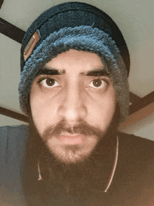 a man with a beard wearing a beanie with a tag on it that says ' abercrombie & fitch '