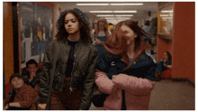 two girls are walking down a hallway with the letter c on their jackets