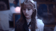 a girl with long hair and bangs is wearing a white dress and black tie .