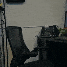 a black office chair sits in front of a desk with a telephone on it