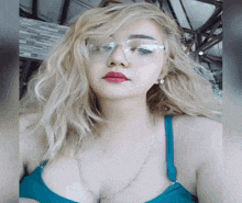 a woman with blonde hair and glasses is wearing a blue bra