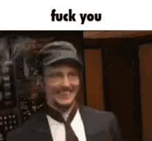a man in a suit and tie is smiling and says fuck you .