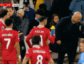 a group of soccer players including m. salah and luis diaz are standing in front of a crowd