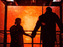 a man and a woman are shaking hands in front of a fire