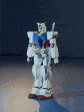 a white and blue robot with red feet is standing on a gray surface