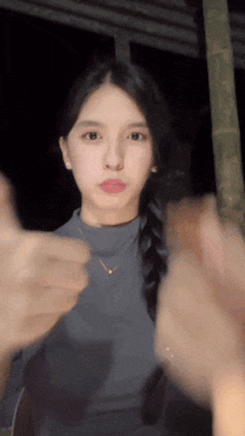 a woman in a braided ponytail giving a thumbs up