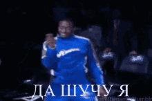 a man in a blue suit is dancing in a dark room with the words da shuchu y written in white