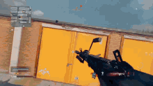 a person is holding a rifle in front of a yellow garage door that says tab