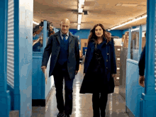 a man and a woman are walking down a hallway in a building