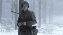 a man in a military uniform is standing in the snow holding a gun