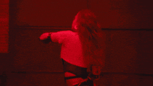 a woman is dancing in a dark room with red lights behind her