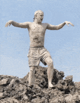 a man covered in mud stands on top of a pile of dirt