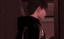a man in a black hoodie is standing in a dark room with his back to the camera
