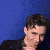 a man in a suit and tie is smiling in front of a blue wall