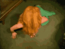 a woman with red hair crawling on the floor