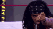 a woman with a bandana on her head is pointing her finger
