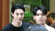 two young men are standing next to each other in a room .