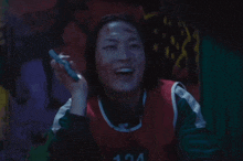 a woman wearing a number 124 jersey is smiling and holding a marker
