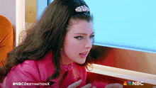 a woman in a pink jacket with the nbc destination x logo on the bottom right