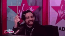 a man is wearing headphones and smiling in front of a microphone in a radio studio .