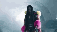 a woman in a fur coat and pink boxing gloves is standing on a stage .