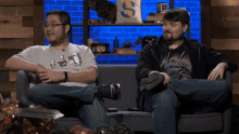 two men are sitting on a couch with one wearing a shirt that says ' i love you ' on it