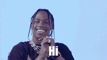 a man with dreadlocks and a necklace is smiling and says hi .